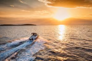 Motorboat cruising across calm water at sunset