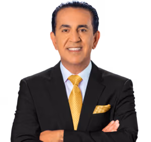 A man with dark hair wearing a black suit, white shirt, and yellow patterned tie stands with arms crossed, smiling confidently at the camera—exuding the professionalism of a Los Angeles Personal Injury Lawyer—against a plain white background.